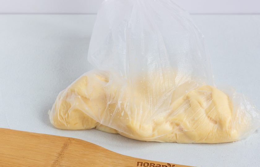 1. Этап. Салат Новогодний подарочек: Наш сыр готов! Развяжите пакет и раскатайте сыр скалкой, не вынимая из пакета, в виде прямоугольника. Длина сырного прямоугольника должна быть немного больше длины салата. Затем разрежьте пакет, достаньте салат из морозилки и выложите на середину раскатанного сыра. 