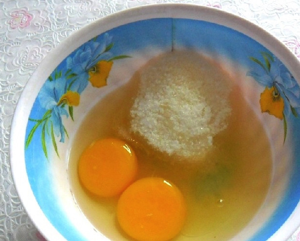 1. Этап. Пышные оладьи с творогом: В миске разбейте яйца. Туда же отправьте сахар и хорошо размешайте его с яйцами при помощи вилки или блендера. Сюда же положите щепотку соли. Дождитесь, пока сахар немного растает.