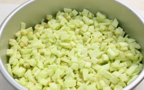 1. Этап. Воздушная шарлотка с яблоками: 3. Жаропрочную форму застелите пергаментом и смажьте сливочным маслом. Яблоки вымойте, обсушите и нарежьте мелкими кубиками. Если они кисловатые, присыпьте сахаром. Выложите на дно формы ровным слоем.