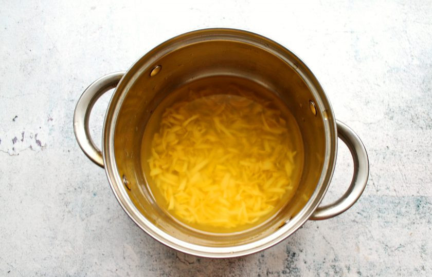 1. Этап. Лимонное желе с медом: С лимона срежьте желтую часть, не задевая белую, порежьте тонкой соломкой и выложите в кастрюлю. Залейте цедру двумя стаканами воды, доведите до кипения на среднем огне. Убавьте огонь и варите в течение 15 минут. Снимите с огня, закройте крышкой и остудите до теплого состояния.