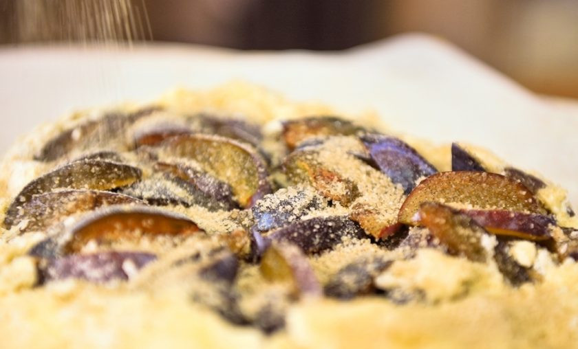 1. Этап. Песочная галета со сливой: Далее переложите тесто в форму для выпечки. В центр выложите сливы. Сверните края, а сверху всыпьте сахар с ванилью.