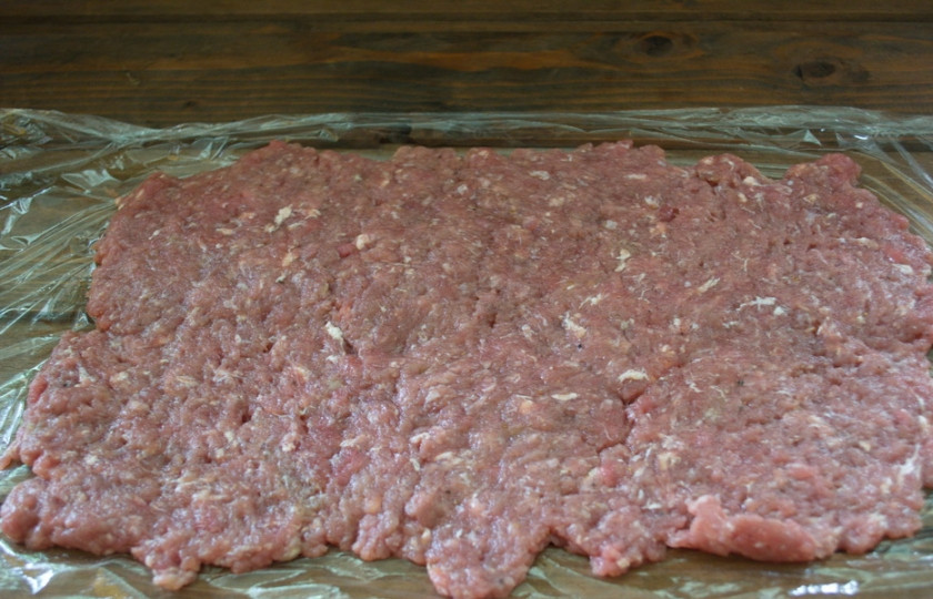 1. Этап. Мясной рулет с грибным соусом: Возьмите пищевую пленку. Разложите ее на столе. Выложите фарш и равномерно распределите по пленке в виде прямоугольника.