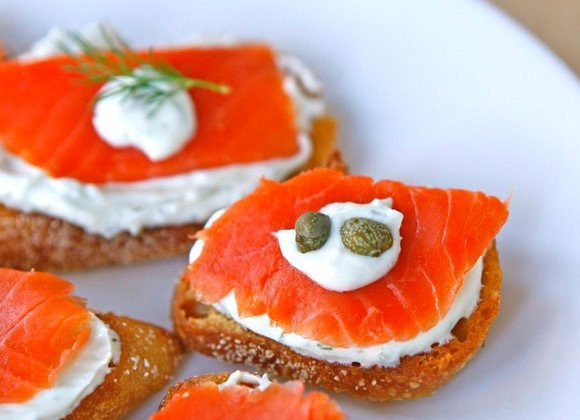 1. Этап. Бутерброды с семгой: 6. На кусочек хлеба выложите немного сырного крема, сверху - рыбку. Капельку соуса и каперсы, например.