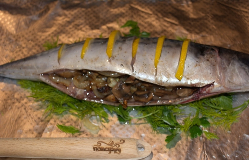 1. Этап. Скумбрия, запеченная с грибами: Фольгу смажьте растительным маслом. Наполните брюшко рыбы подготовленной начинкой. Утрамбуйте. На смазанный лист фольги выложите нарезанную зелень. Она предотвратит возможное пригорание рыбы. На зелень выложите тушку рыбы. Закройте её листом фольги. Закрепите края так, чтобы образующийся пар и сок не вытекали.