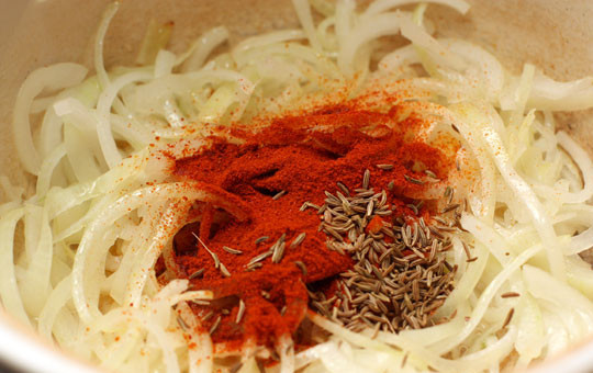 1. Этап. Гуляш из свинины с помидорами: Добавляем к луку паприку и тмин, перемешиваем и готовим минутку-полторы.