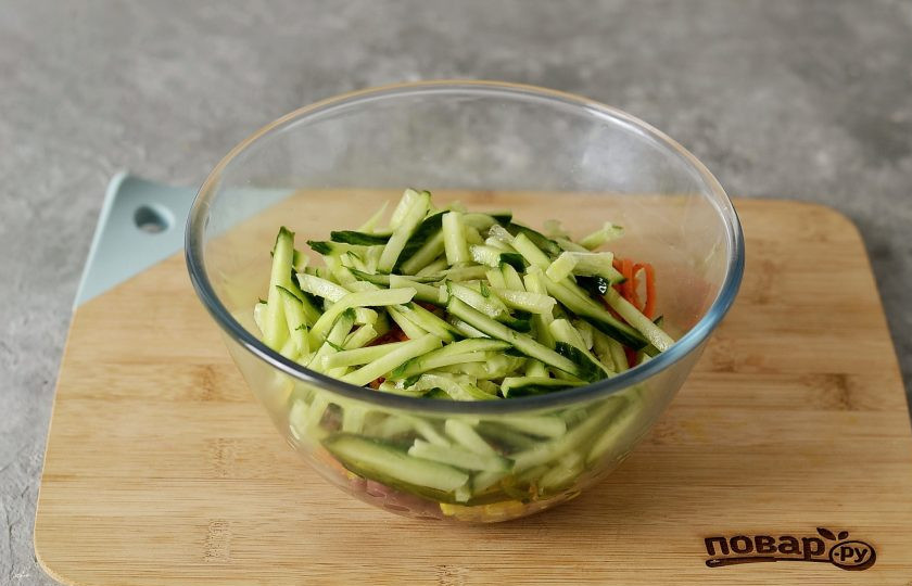 1. Этап. Салат с корейской морковью: Огурец нарежьте соломкой. Переложите в миску.