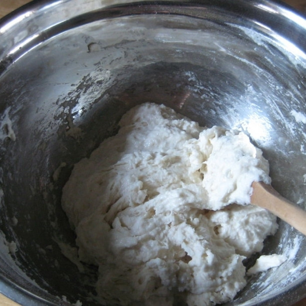 1. Этап. Пицца по-домашнему: Переливаем получившуюся смесь в большую миску, туда же просеиваем муку. Деревянной ложкой или лопаткой перемешиваем тесто. Не переживайте, что у вас будет получаться очень клейкое тесто, не похожее на обычное тесто для пиццы. Так и должно быть, благодаря этому тесто потом получается очень нежным, мягким.