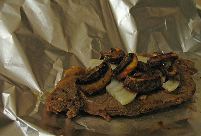 1. Этап. Ромштекс из свинины в духовке: Разогрели духовку до 190 градусов. Обжарили в той же сковороде грибы, затем выложили их поверх лука, полили соусом со сковороды.