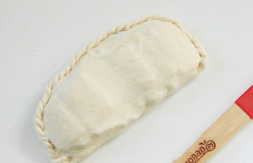 1. Этап. Кальцоне с цукини, оливками и моцареллой: Накройте начинку второй половиной теста и защипните края косичкой.