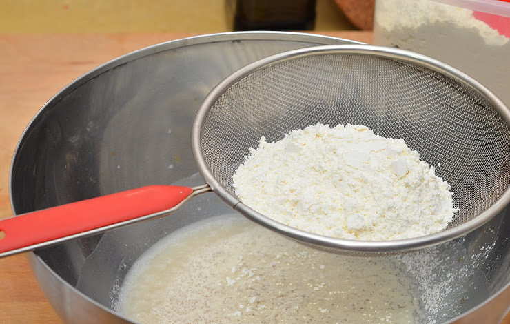 1. Этап. Пирожки с рыбой: 3. Теперь можно добавить щепотку соли и постепенно всыпать просеянную муку, тщательно перемешивая.