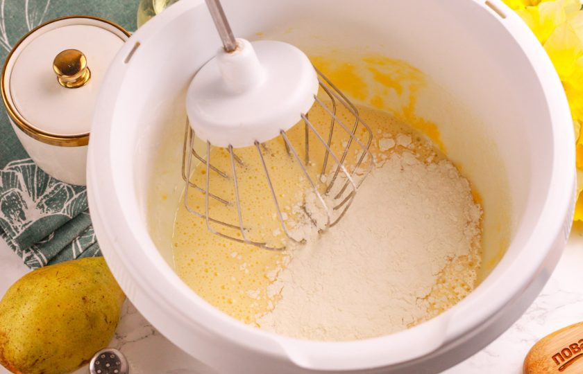 1. Этап. Шарлотка с грушами в аэрогриле: Всыпьте по частям пшеничную муку высшего сорта, замешивая ее венчиком, но не взбивая.