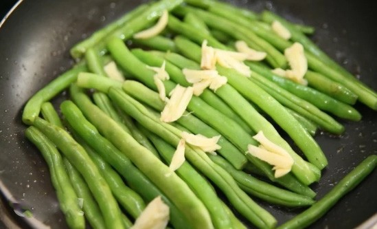 1. Stage. Young beans in pods: Transfer the beans to the pan, add the garlic crushed by the flat side of the knife, salt and pepper to taste. Fry for 5-7 minutes, stirring occasionally.