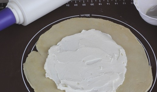 1. Этап. Галета со сливами: Тесто раскатываем в круг приблизительно диаметром 30-32 см, равномерно распределяем крахмал не доходя до краев и поверх наносим слой творожного сыра Hochland. Хорошо это делать сразу на пекарской бумаге, чтобы было удобно затем перенести галету на противень.