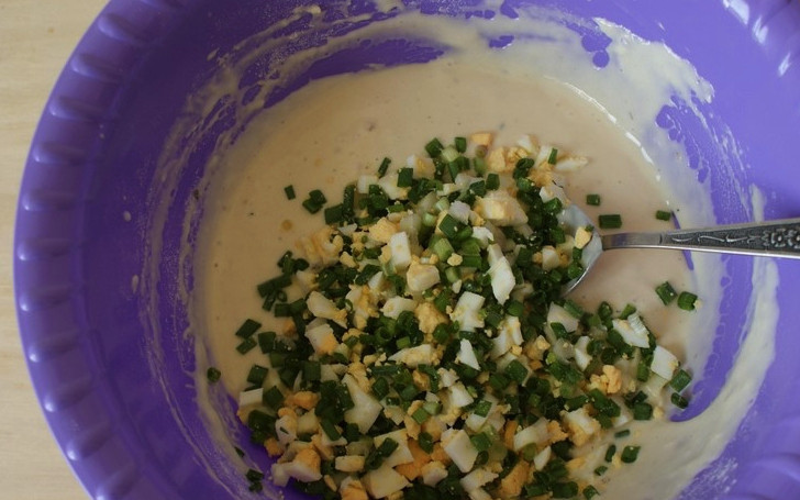 1. Этап. Оладьи с луком и яйцом на кефире: Отваренные вкрутую яйца отправьте на несколько секунд под холодную воду. Затем очистите их и мелко нарежьте. Так же нарежьте стебли зелёного лука. Отправьте яйца с луком в тесто и перемешайте.