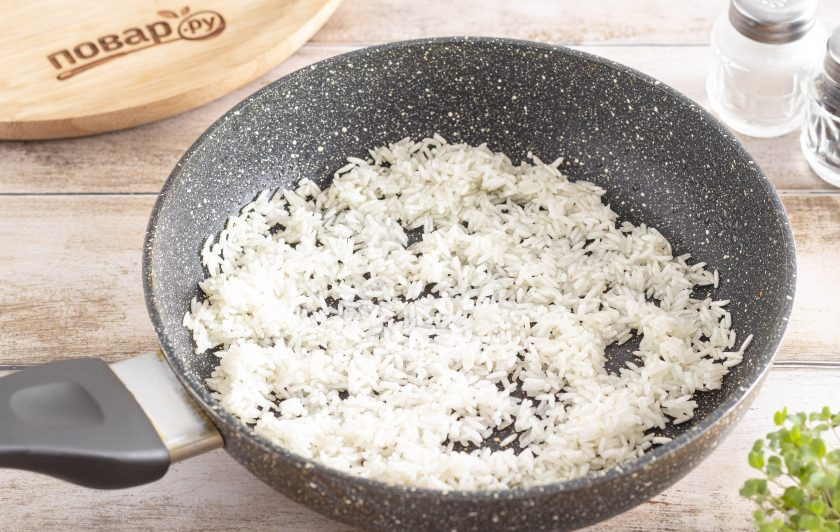1. Этап. Рис жареный на сковороде: Рис промойте до прозрачности и откиньте на сито. Добавьте рис в сковороду и жарьте его 5 минут. Он должен стать в начале прозрачным, а затем приобрести легкий золотистый оттенок.