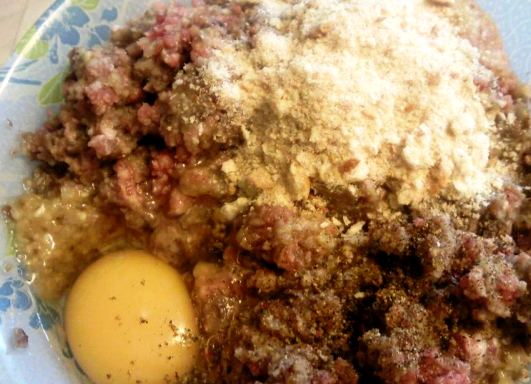 1. Этап. Биточки в томатном соусе: Теперь в глубокой миске соединяем фарш, приготовленную в блендере смесь, яйцо и сухари, добавляем специи и соль по вкусу. Тщательно вымешиваем фарш и даем ему минут 15 постоять, чтобы сухари немного размокли.