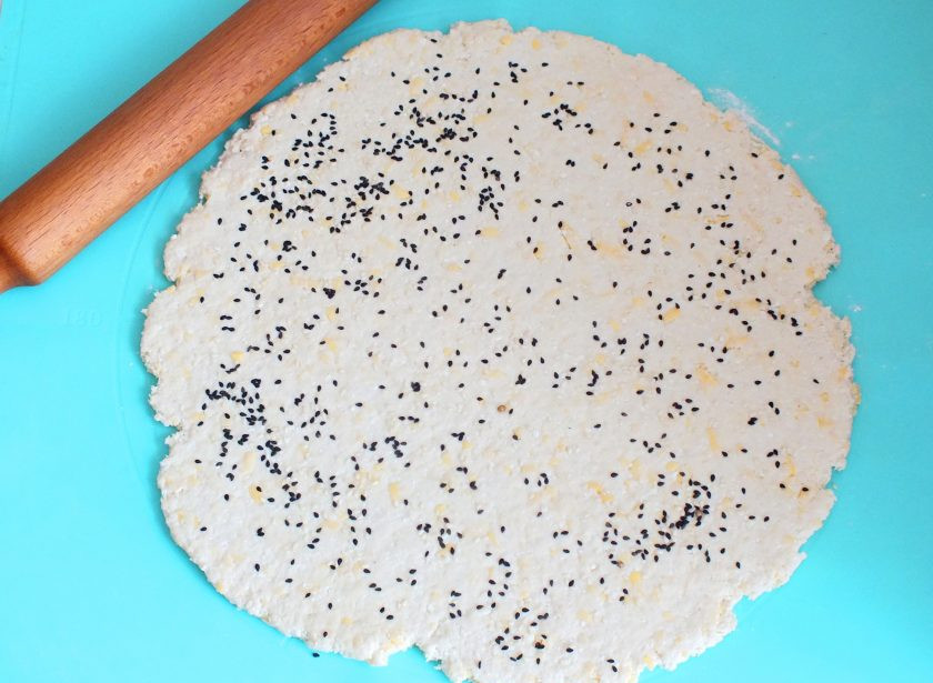 1. Этап. Творожное печенье с сыром: На рабочей поверхности раскатайте тесто. Посыпьте сверху семенами кунжута, слегка прокатайте скалкой.