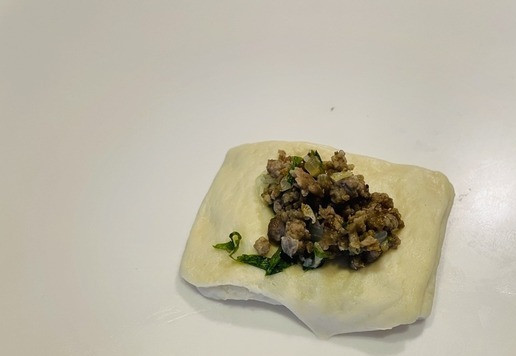 1. Этап. Мясные слоено-дрожжевые пирожки: Кладем начинку (чайную ложку с горкой) и закрываем на уголок. Достаточно просто прижать пальцами по краю.