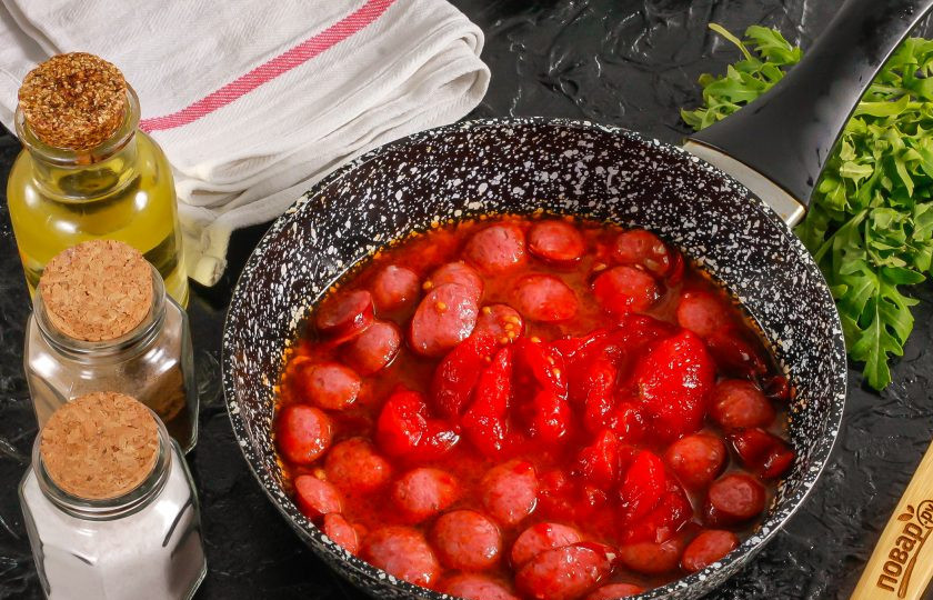 1. Этап. Макароны с охотничьими колбасками: Выложите в сковороду консервированные томаты без кожуры или замените их томатной пастой, разведенной в небольшом количестве воды. Томаты помните вилкой, посолите и поперчите. Потушите весь соус примерно 2-3 минуты.