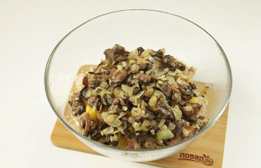1. Этап. Салат Ананас с курицей и сыром: Лук нарежьте кубиками и обжарьте с грибами на сливочном масле до готовности.