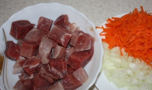 1. Этап. Свинина в мультиварке-скороварке: Мясо промойте и нарежьте кусочками 3 на 3 см. Лук почистите и нашинкуйте. Морковь помойте, почистите и натрите на крупной тёрке.