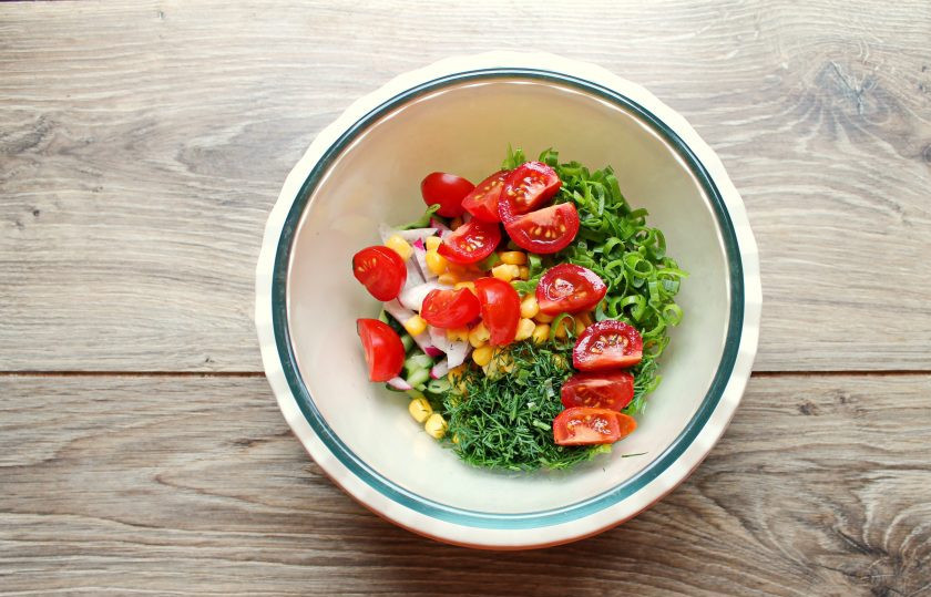 1. Этап. Постный салат с кукурузой: Помидоры разрежьте пополам или на четыре части и добавьте в салат.