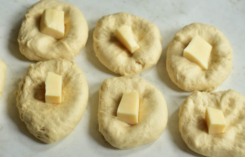 1. Этап. Пампушки с сыром: Каждый немного придавите и выложите в центр по кусочку твердого сыра.