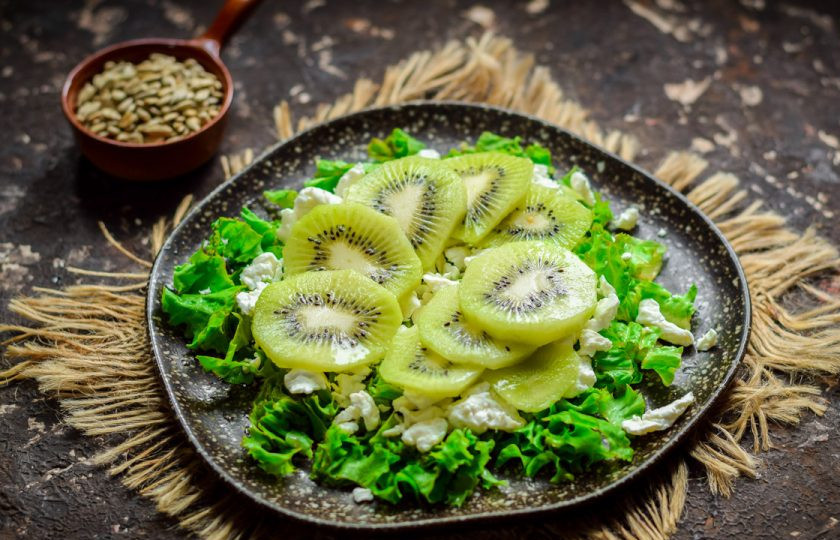 1. Этап. Зеленый салат с киви: Киви очистите и нарежьте кружочками. После киви выложите поверх творога.