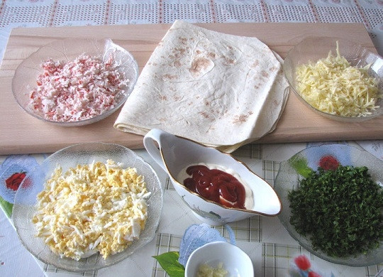 1. Этап. Рулеты из лаваша с крабовыми палочками: 2. Яйца предварительно отварите вкрутую, остудите и очистите. Натрите на мелкую терку вместе с сыром и крабовыми палочками. Пропустите через пресс чеснок. Измельчите зелень. В качестве соуса в данном случае используется майонез с кетчупом — вариант на скорую руку.