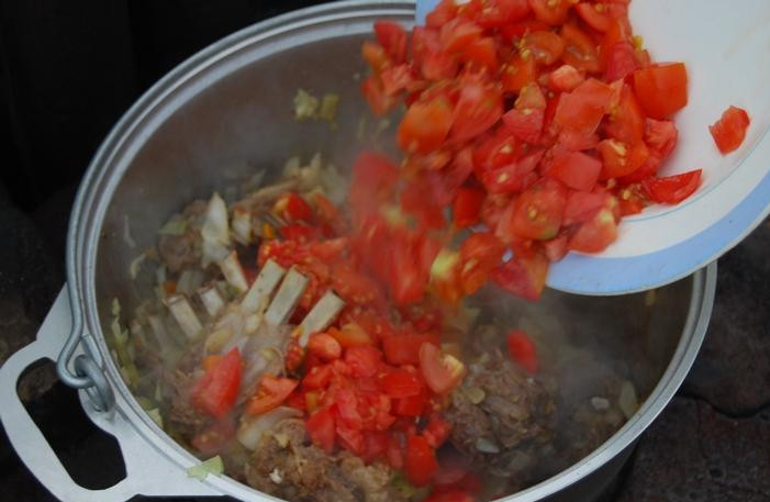1. Этап. Шулюм из баранины на природе: 4. После капусты - измельченные помидоры. Сразу же заливаем шулюм водой, чтобы покрыла овощи и мясо. Тушим, пока капуста не станет мягкой.