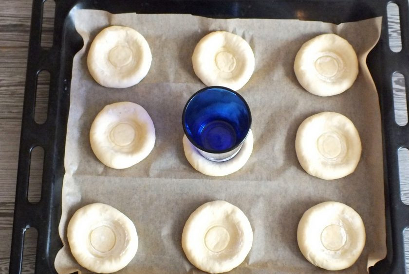 1. Этап. Ватрушки с бананом: По истечении времени с помощью стакана сделайте углубления в тестяных заготовках.