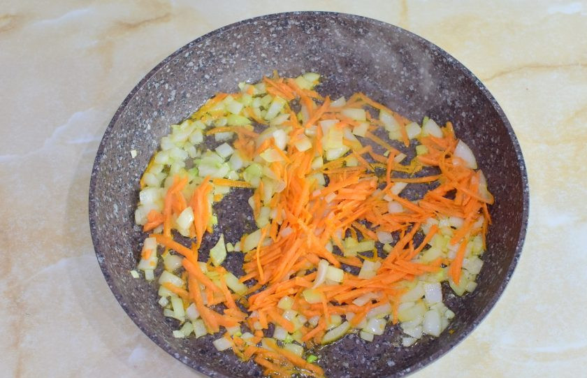 1. Этап. Макароны с фаршем и белыми грибами: Лук и морковь очистите и ополосните от загрязнений. Лук мелко нарежьте, а морковь потрите на крупной терке. Обжарьте овощи 2-3 минуты с добавлением растительного масла.