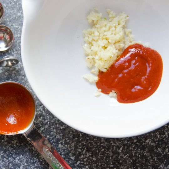 1. Этап. Острые куриные крылышки с медом: Сделайте соус. Измельчите чеснок. Соедините его с соусом шрирача в миске.