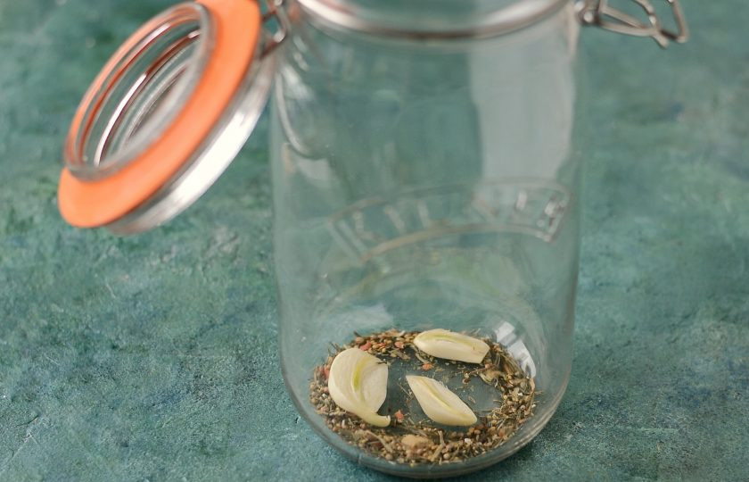 1. Этап. Маринованные огурцы на 1.5 литровую банку: На дно заранее стерилизованной банки выложите половину приправы и чеснока.