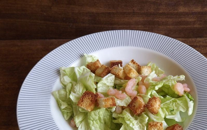 1. Этап. Салат Цезарь лучший: Салат вымойте и обсушите. Его листья порвите руками и выложите на тарелку. Добавьте к зелени отварные и очищенные и хлебные гренки, оставив немного для украшения салата.