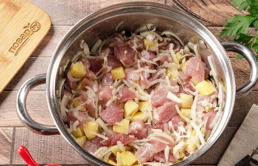 1. Этап. Жаркое в горшочке из теста: Мясо и картофель нарежьте небольшими кубиками. Лук можно нарезать произвольно. Добавьте по вкусу соль, молотый перец и специи. Перемешайте, а затем помните руками, чтобы лук пустил сок. Можете приготовить любую другую начинку на свой вкус или добавить сезонные овощи.