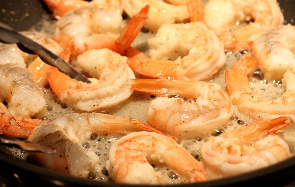 1. Этап. Салат с креветками: Добавьте сухой чеснок и перец. Помешивайте креветки лопаткой.