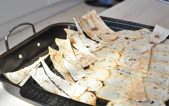 1. Этап. Карпаччо из говяжьей вырезки: Багет отправьте в морозилку. Когда он замерзнет, нарежьте его на максимально тонкие ломтики. Это удобнее делать при помощи слайсера, но можно и обычным острым ножом. Помимо багета вы можете взять кусочки лаваша. Выложите хлеб на противень и при температуре сто двадцать градусов сушите его в духовке полчаса.