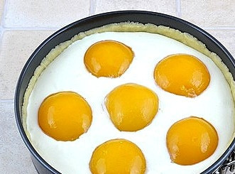 1. Этап. Творожный пирог с персиками: Достанем форму с тестом, выльем начинку и уложим половинки персиков. Выпекать будем в разогретой до 180С духовке в течение часа.