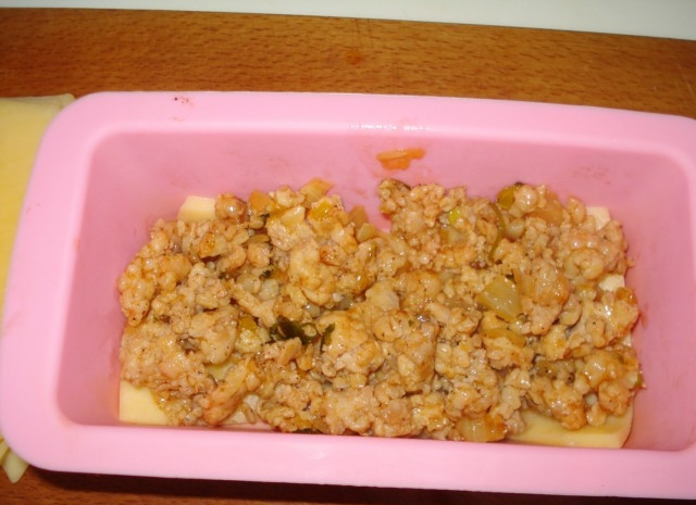 1. Этап. Лазанья сырная: В форму для запекания первым слоем выложите сыр, следом обжаренный куриный фарш с луком.