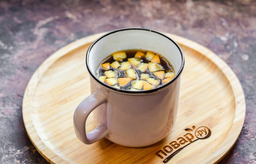 1. Этап. Безалкогольный коктейль на Новый год: 350 мл. воды доведите до кипения. Половину апельсина разрежьте пополам. Одну половину нарежьте мелкими кубиками и переложите в чашку, туда же всыпьте чай и залейте кипяток. Дайте завариться чаю и оставьте до остывания.