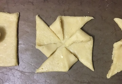 1. Этап. Печенье Вертушки: Перенесите квадраты на подготовленный противень, располагая их на расстоянии 2,5 см друг от друга. Используя острый нож или колесо для пиццы, сделайте надрезы шириной 3,5-4 см по диагонали от каждого угла, недоходя до центра. Центральная часть, где будет располагаться начинка должна быть целая. Если вы используете силиконовый коврик, сделайте надрезы на рабочей поверхности, затем аккуратно перенесите квадраты на противень.