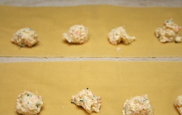 1. Этап. Равиоли с креветками и рикоттой: 2. Выложить 1 чайную ложку начинки через каждые 7,5 см листа пасты. Смочить водой края теста. Если лист пасты не менее 10 см в длину, сложить его пополам вдоль начинки. Если лист пасты меньше 10 см, положить сверху второй лист пасты и, используя нож для пиццы, вырезать равиоли. Повторить с оставшимися ингредиентами.