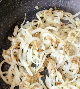 1. Этап. Шницель из говяжьей печени: На смеси растительного и сливочного масла (2/3 от общего объёма), обжарить лук до зарумянивания, перед готовностью добавить чеснок, жарить ещё 1-2 минуты.