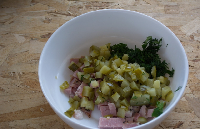 1. Этап. Салат Мужской идеал: Соленый огурец и зелень нарезаем. Нарезанные продукты поместите в салатник.