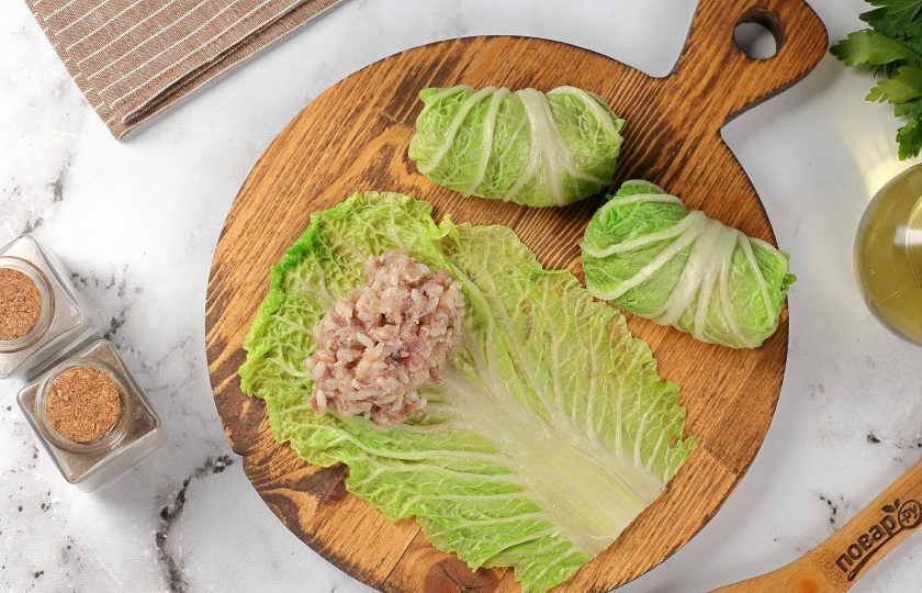 1. Этап. Голубцы из пекинской капусты: На каждый лист пекинской капусты выложите небольшое количество фарша и заверните фарш в лист, придавая форму голубца.