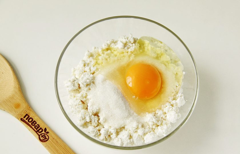 1. Этап. Сырники с кокосовой стружкой: Добавьте к творогу яйцо и сахар.