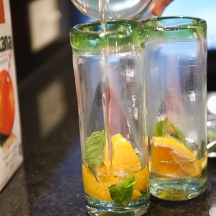 1. Этап. Апельсиновый мохито: 2. Промойте листики мяты. В высокий стакан положите дольку или две апельсина, несколько листиков мяты, добавьте ложечку сахара или влейте сиропа.