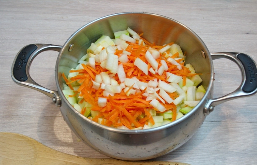 1. Этап. Кабачковая икра без жарки: Нарежьте репчатый лук, а морковь натрите на крупной терке. Положите эти овощи к кабачкам. Влейте в кастюлю 1 стакан воды. Поставьте ее на огонь и тушите около 30 минут. Помешивайте.