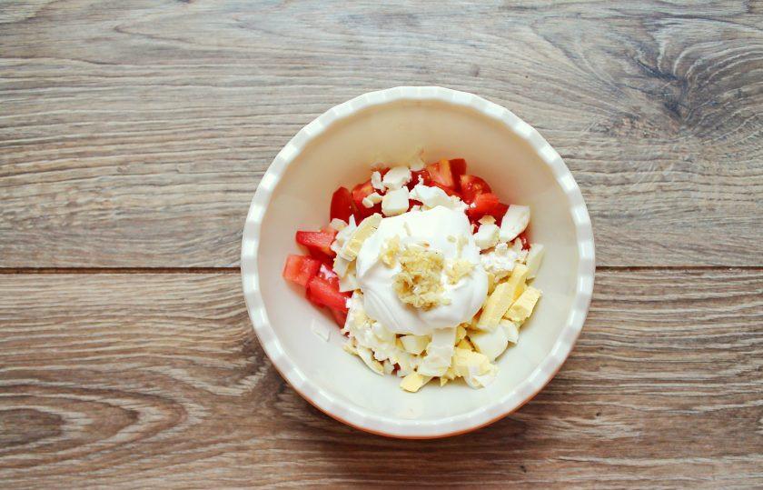 1. Этап. Салат с рикоттой и помидорами: Выложите сметану и добавьте измельченный чеснок. Салат посолите и перемешайте.